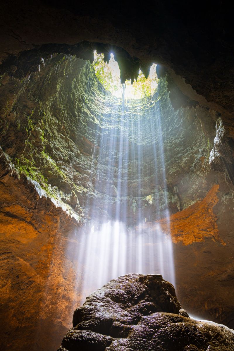 Beams of sunlight falling into Jomblang cave through the sinkhole opening