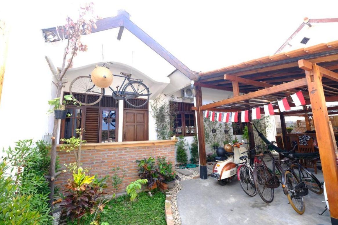 Wood Stone Homestay front garden with wooden pergola, vintage bicycles and scooter in Yogyakarta